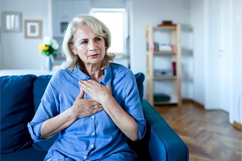 A woman holding her chest, looking distressed.