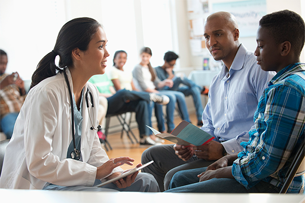 Female provider talking with a father and teen son